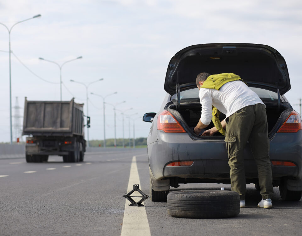 replacing wheel car-road man doing tyre-work-sidelines-Where-to get best personal Tyres in Oldham scaled.jpg