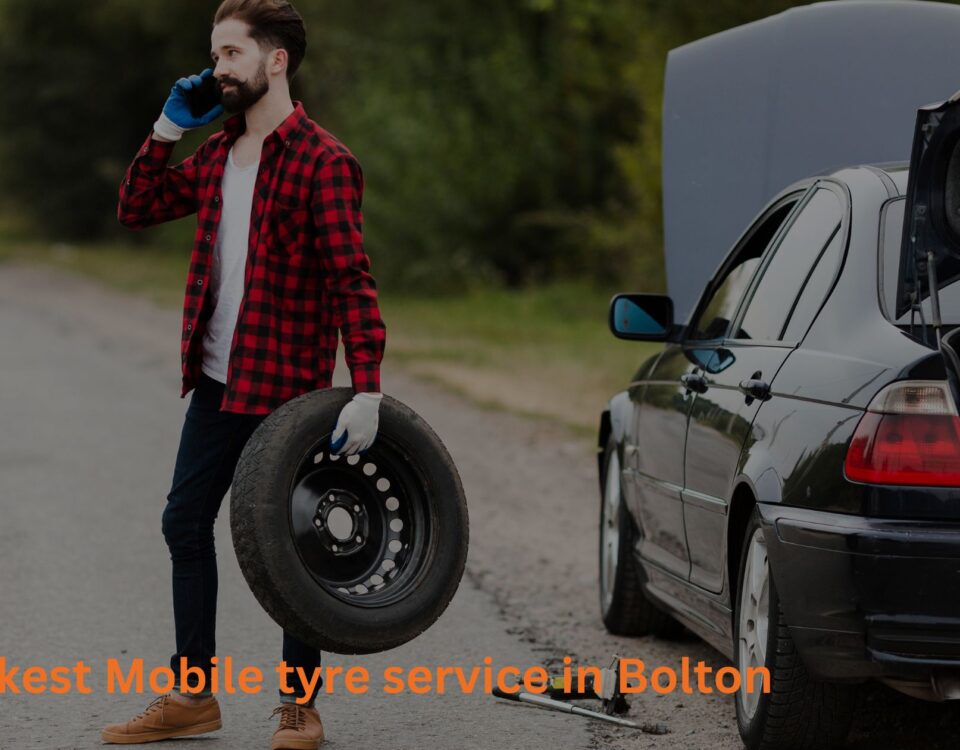 a guy busy on phone and changing tyre at Mobile tyre services in Bolton