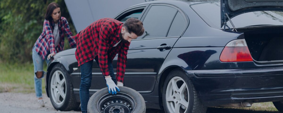 A tyre Mechanic bent down to pick the new tyre to install in the car-The Most Professional tyre rescue services Denton - Greater Manchester in 2024